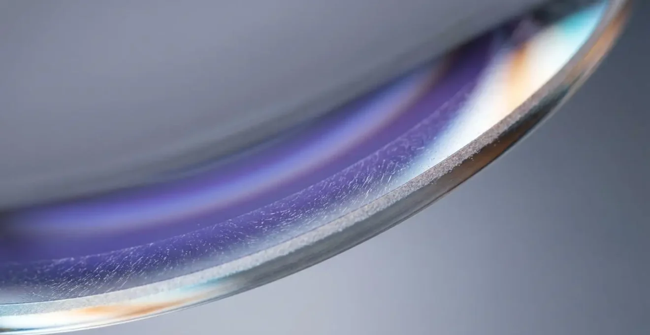 Extreme macro close-up of blue light filtering lens showing purplish-blue coating reflection with shallow depth of field