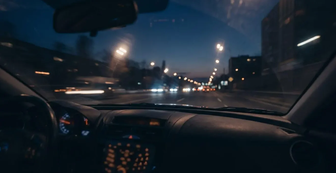 Wide environmental shot depicting challenging night driving conditions with light scatter effects and reduced visibility illustrating cataract-related visual impairment